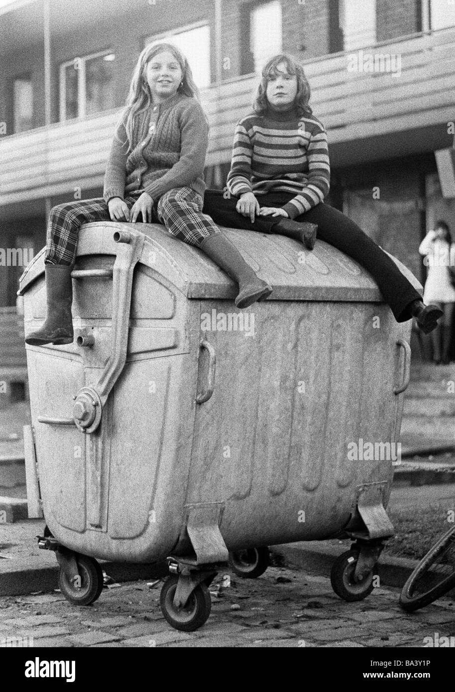Seventies, black and white photo, people, children, two girls sitting on a refuse container, street kids, aged 10 to 13 years Stock Photo