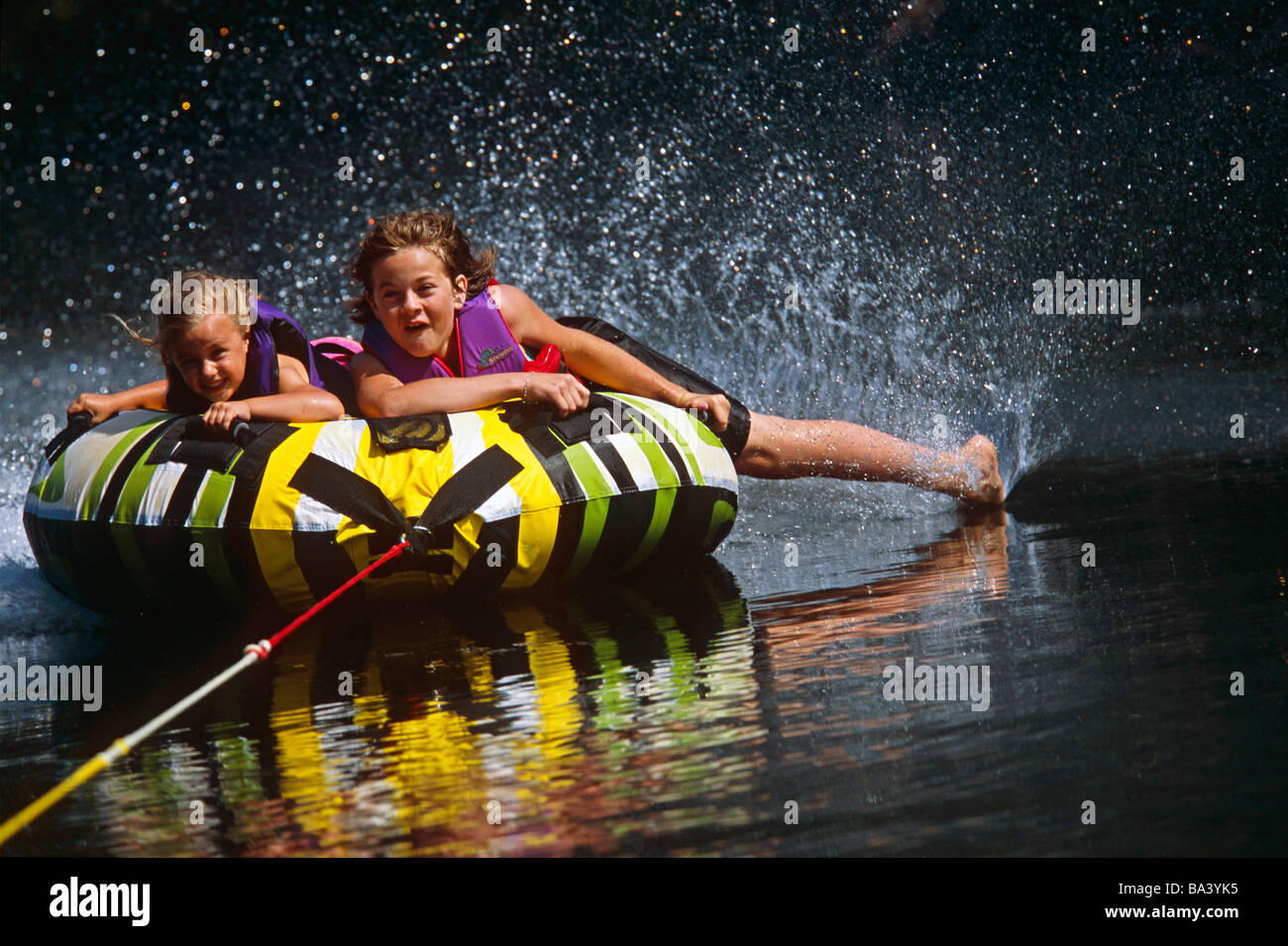 Children riding float tube behind boat on Moose River, Kenai Peninsula