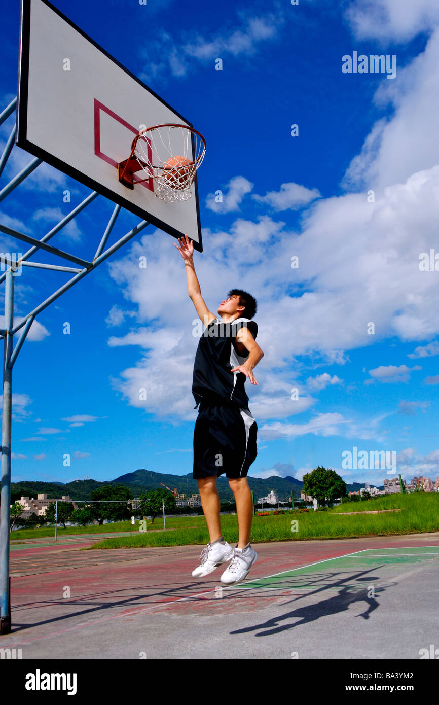 Teenage boy throwing basketball through net Stock Photo Alamy