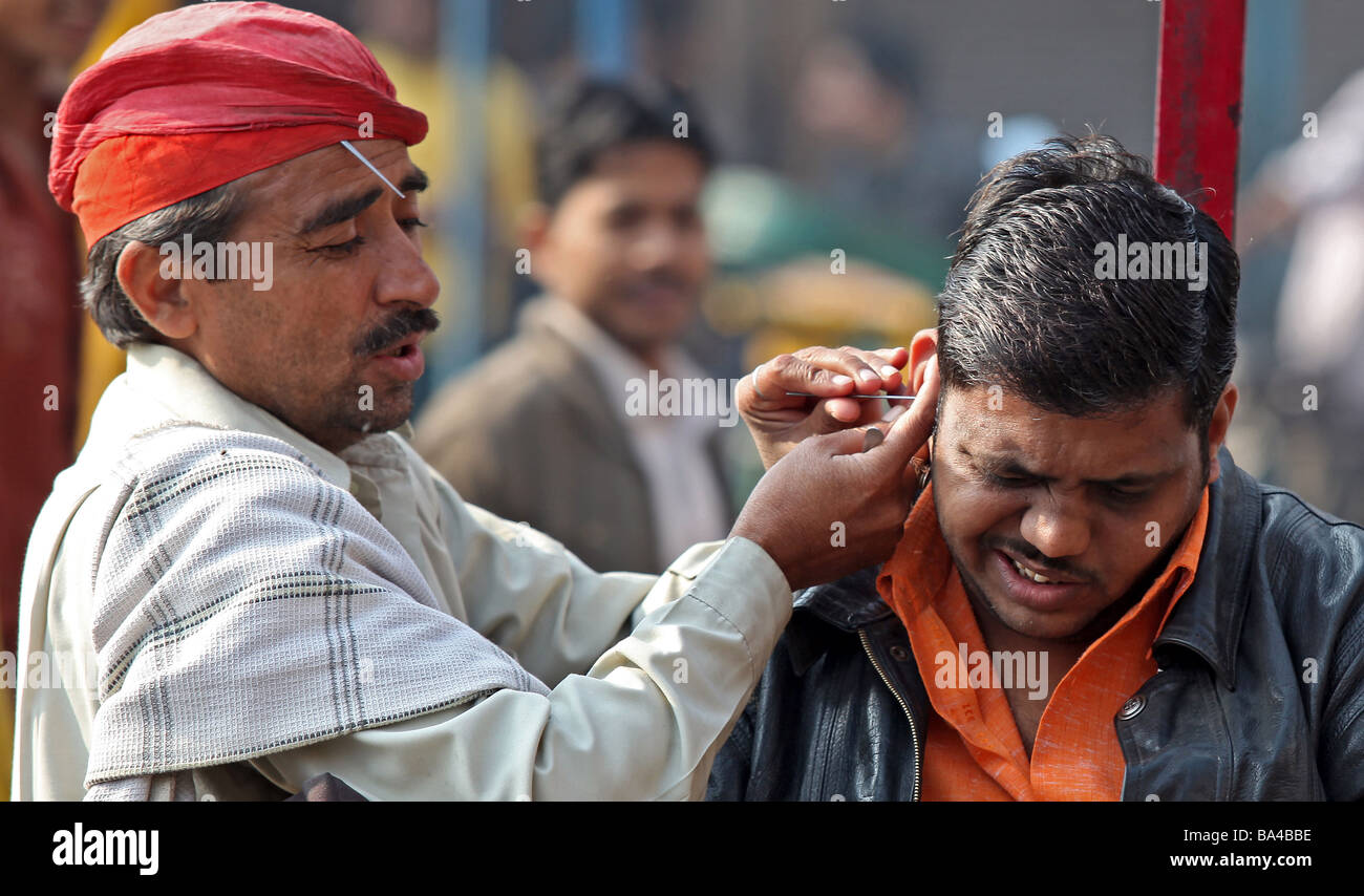 An ear cleaner goes about his business in Old Delhi's Chandi Chowk India keeping the local people hearing clearly Stock Photo