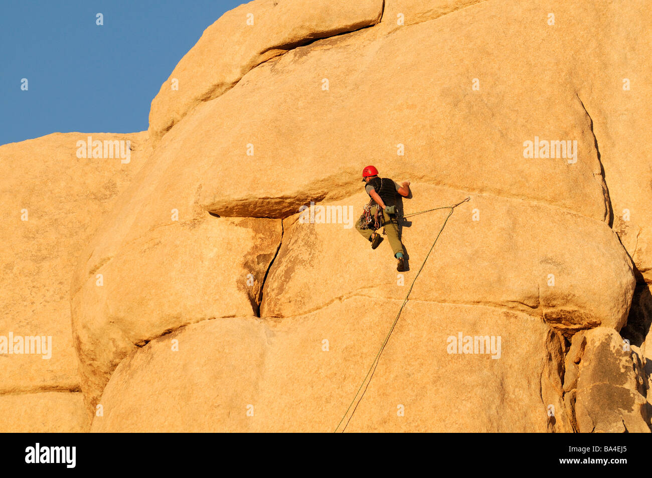 one rock climber man getting ready to climb a rock wall face pinnacle Hidden Valley Joshua Tree National Park Stock Photo