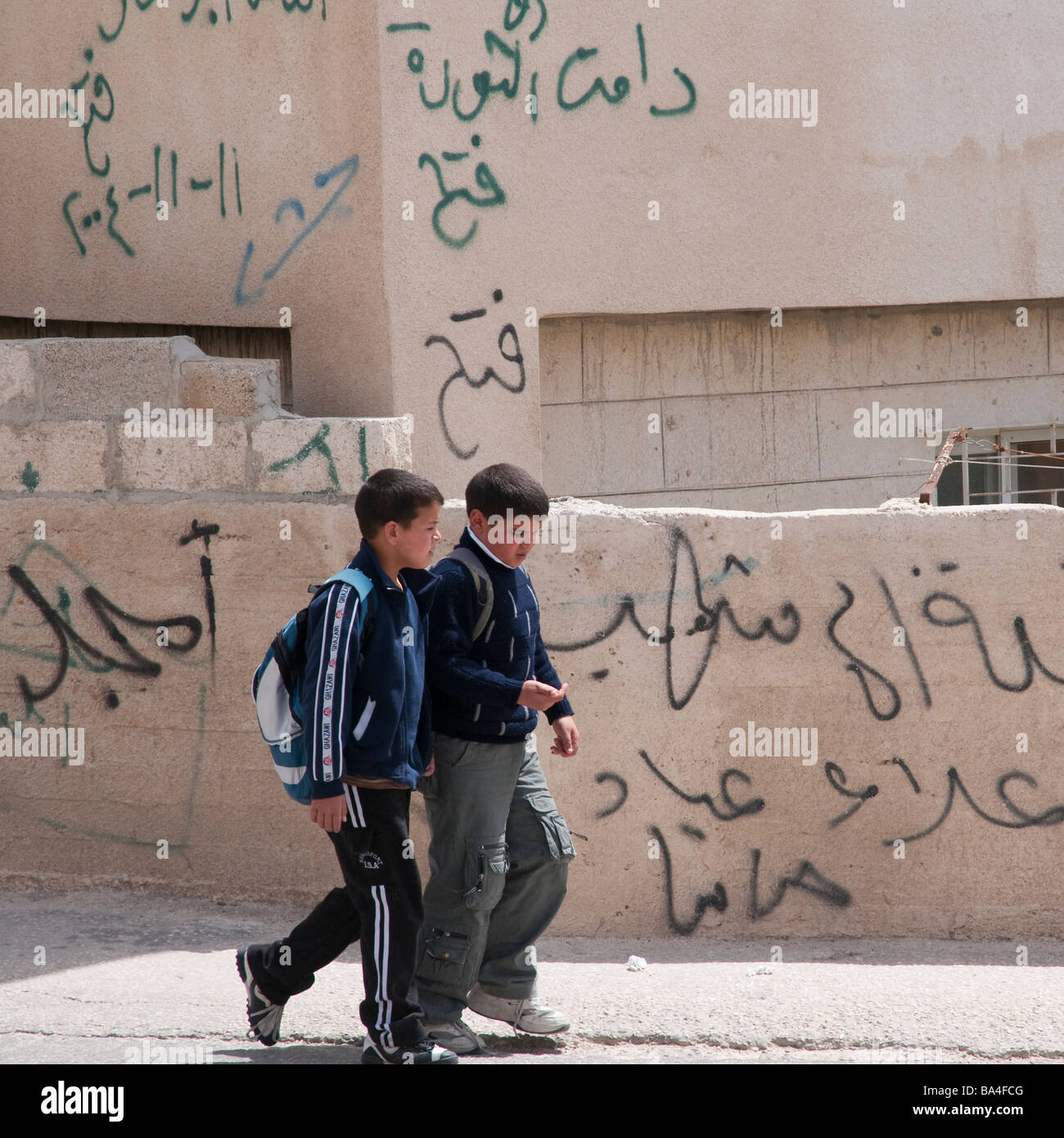 Palestinian Authority Bethlehem Aida refugee camp boys walking passed walls graffitis in the street Stock Photo