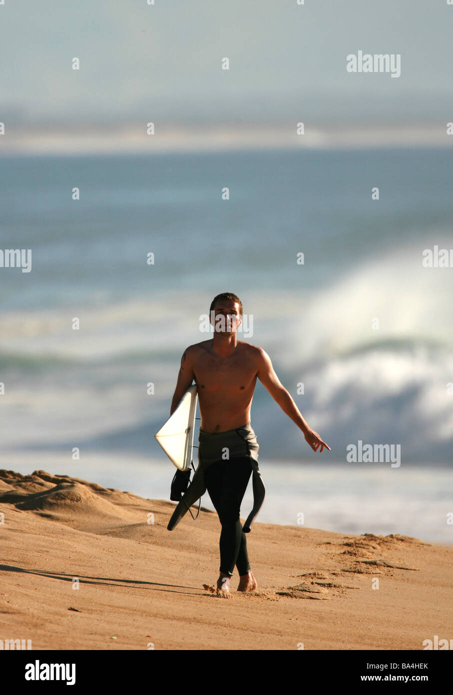 A Surfer walking along the beach with his surfboard Stock Photo - Alamy