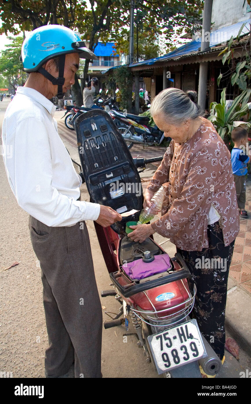 Vietnamese man purchasing one liter of gasoline from a woman on the street in Hue Vietnam Stock Photo