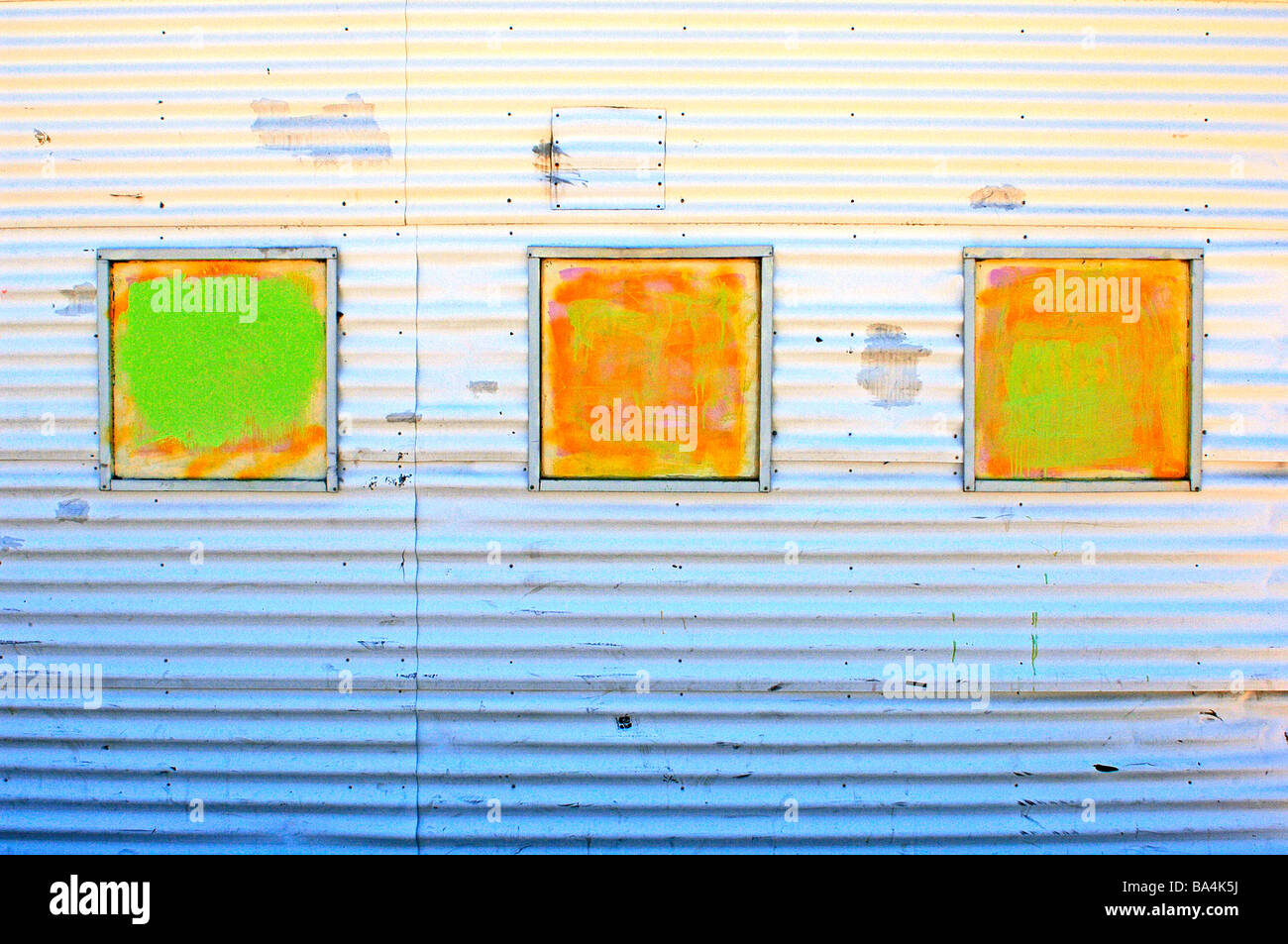 Wide angle fine art shot of brightly painted hand  windows on a corrugated metal building Stock Photo