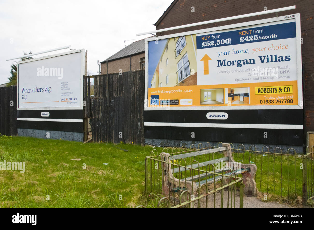 Advertising billboards for ING DIRECT and local house sales on hoardings overlooking small park area in Newport South Wales UK Stock Photo