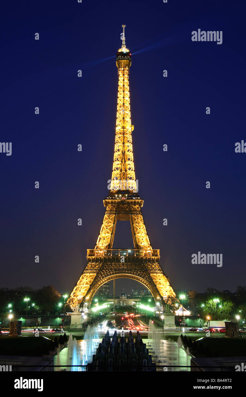 Eiffel Tower Golden Glow At Night From Trocadero Gardens Paris France // PARIS, France — The Eiffel Tower, illuminated with golden lights against the night sky, is viewed from the Jardins du Trocadéro (also known as Trocadero Gardens). This 330-meter (1,083-foot) iron lattice tower, designed by Gustave Eiffel, was completed in 1889 for the Exposition Universelle. Initially a temporary installation, it became a permanent symbol of France and its nightly light show is synonymous with Paris tourism. The tower's illumination system, installed in 2000, uses 20,000 bulbs to create the golden glow vi Stock Photo