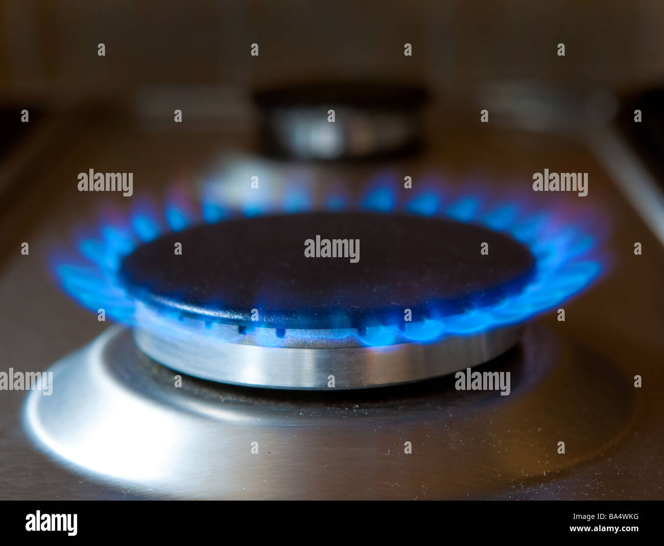 Blue gas flame burning on stainless steel gas hob top stove burner in
