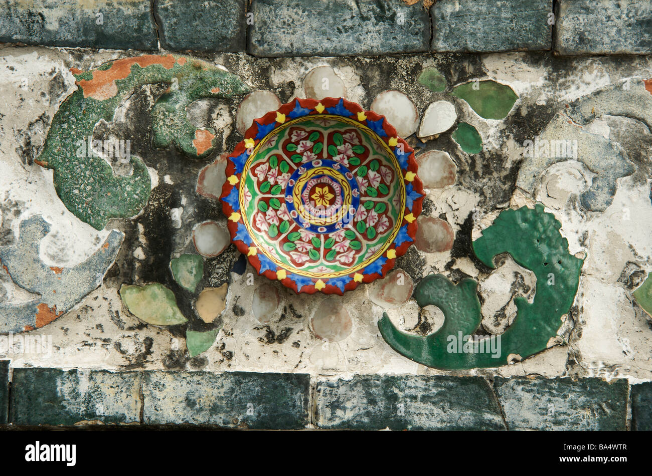 A coloured ceramic plate decorates a temple wall in Bangkok Stock Photo