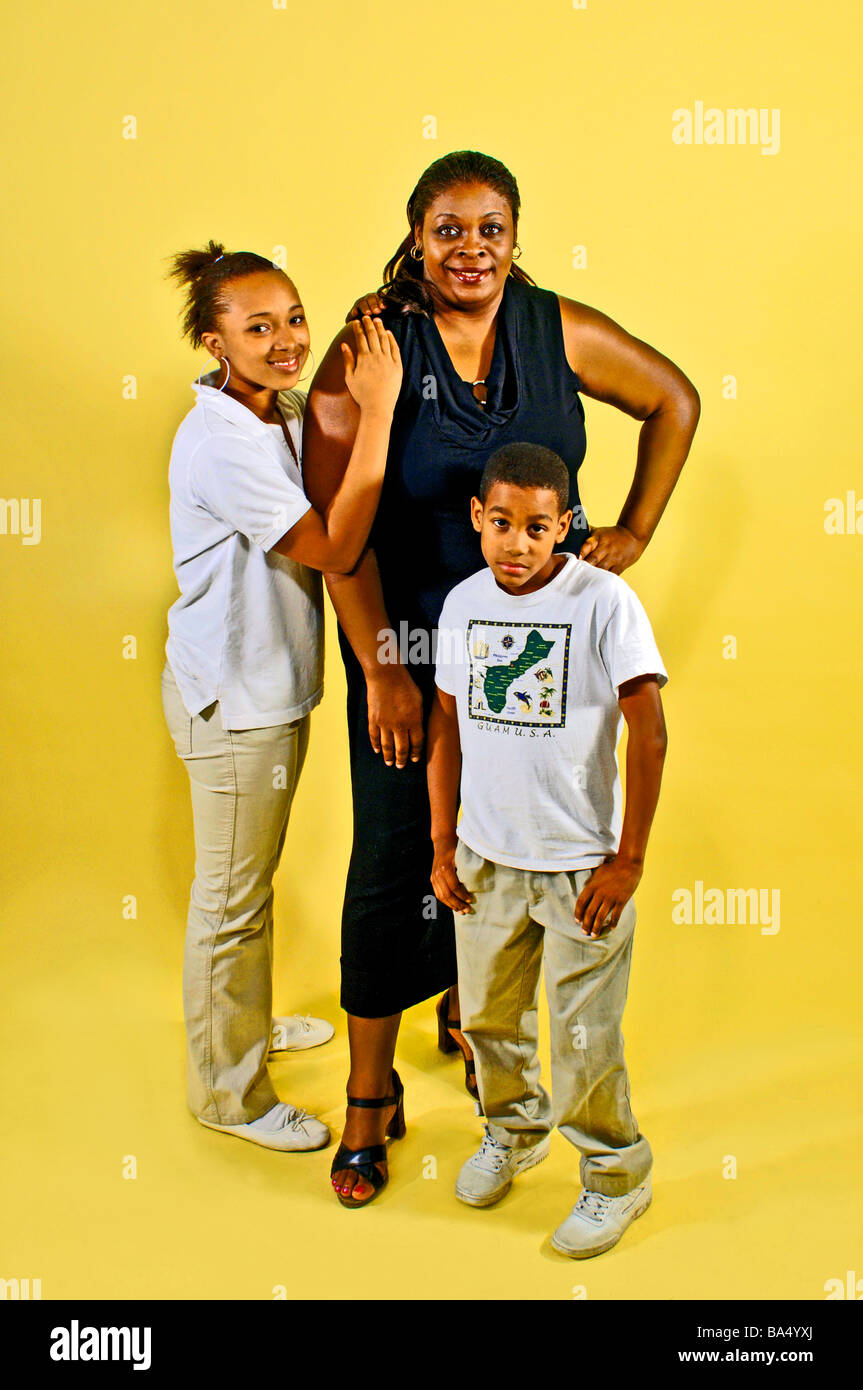 Ethnic single parent guardian poses with two child dependents on a bright yellow background