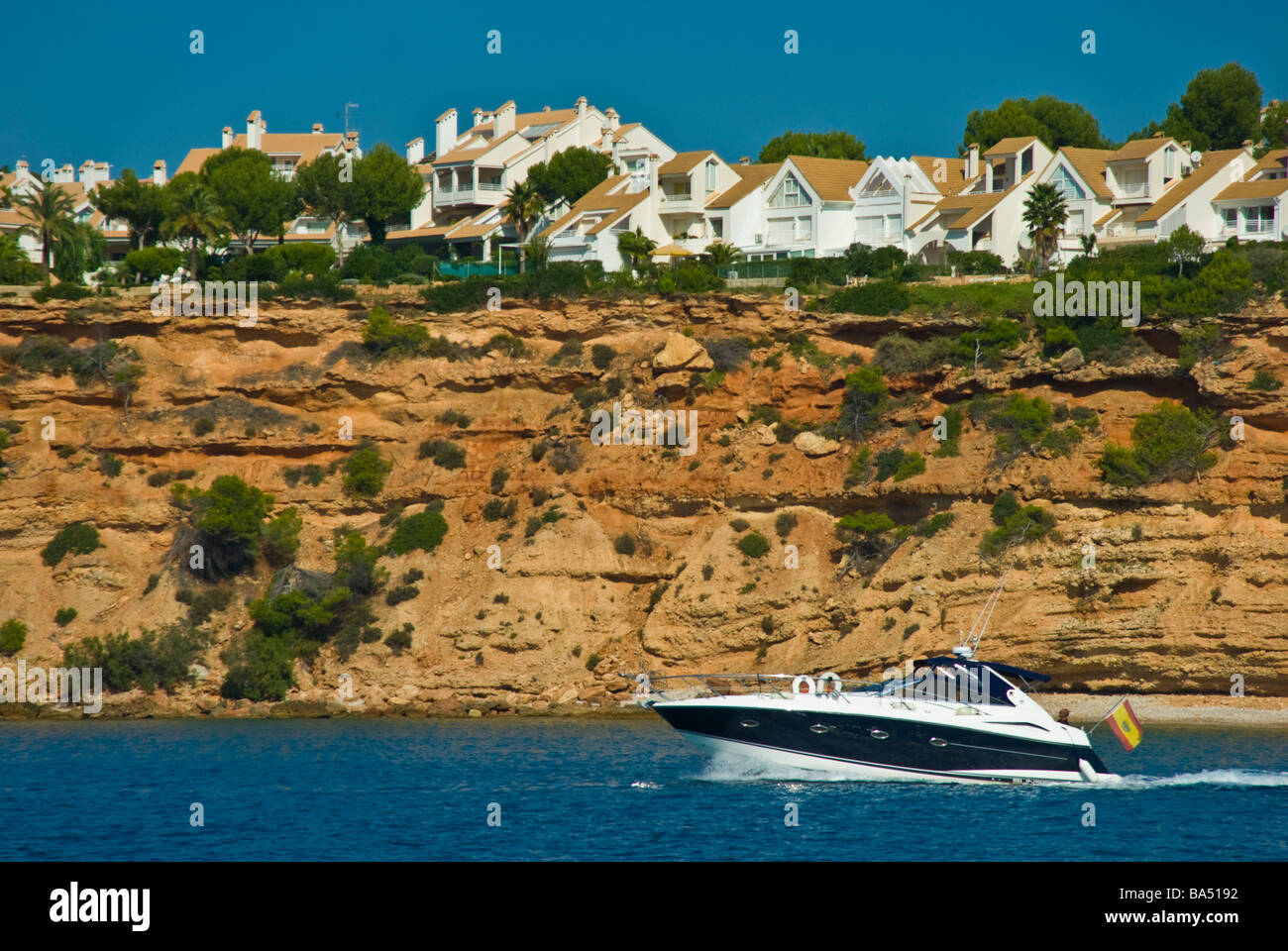 Powerboat in front of cliff with houses at Prot Adriano Majorca Spain | Motoryacht Klippe mit Häusern bei Port Adriano Stock Photo