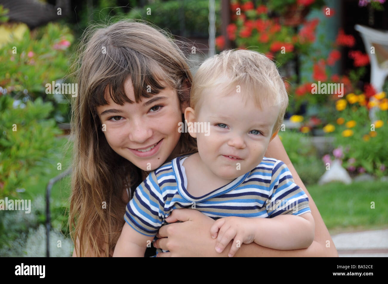 brownhaired French young girl hugs her very fairhaired German baby