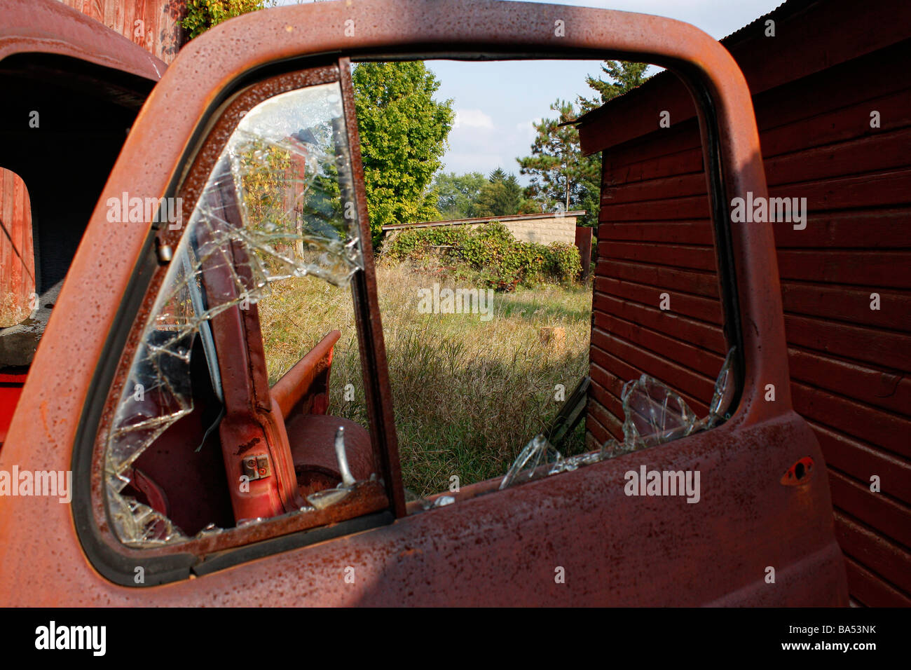 Abandoned a rusty old red car in open rusty antique car in the field with wooden barn Michigan USA old vintage fashioned wallpapers wallpaper hi-res Stock Photo