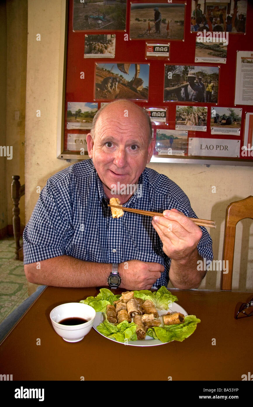 American man eating a spring roll with chopstix in Quang Tri Province Vietnam Stock Photo