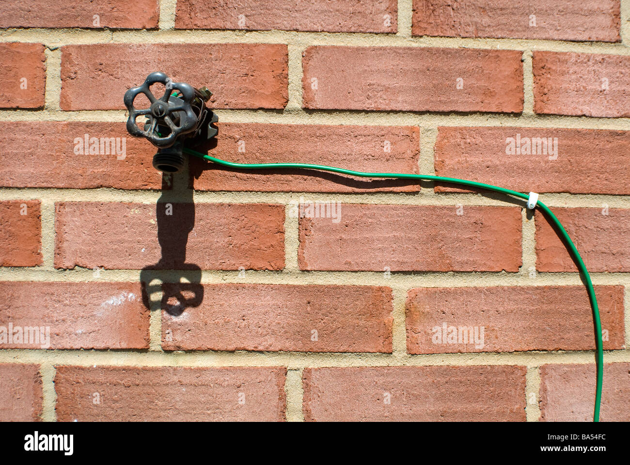 Electric Wire Running From An Outside Faucet On A Brick Wall Stock Photo Alamy