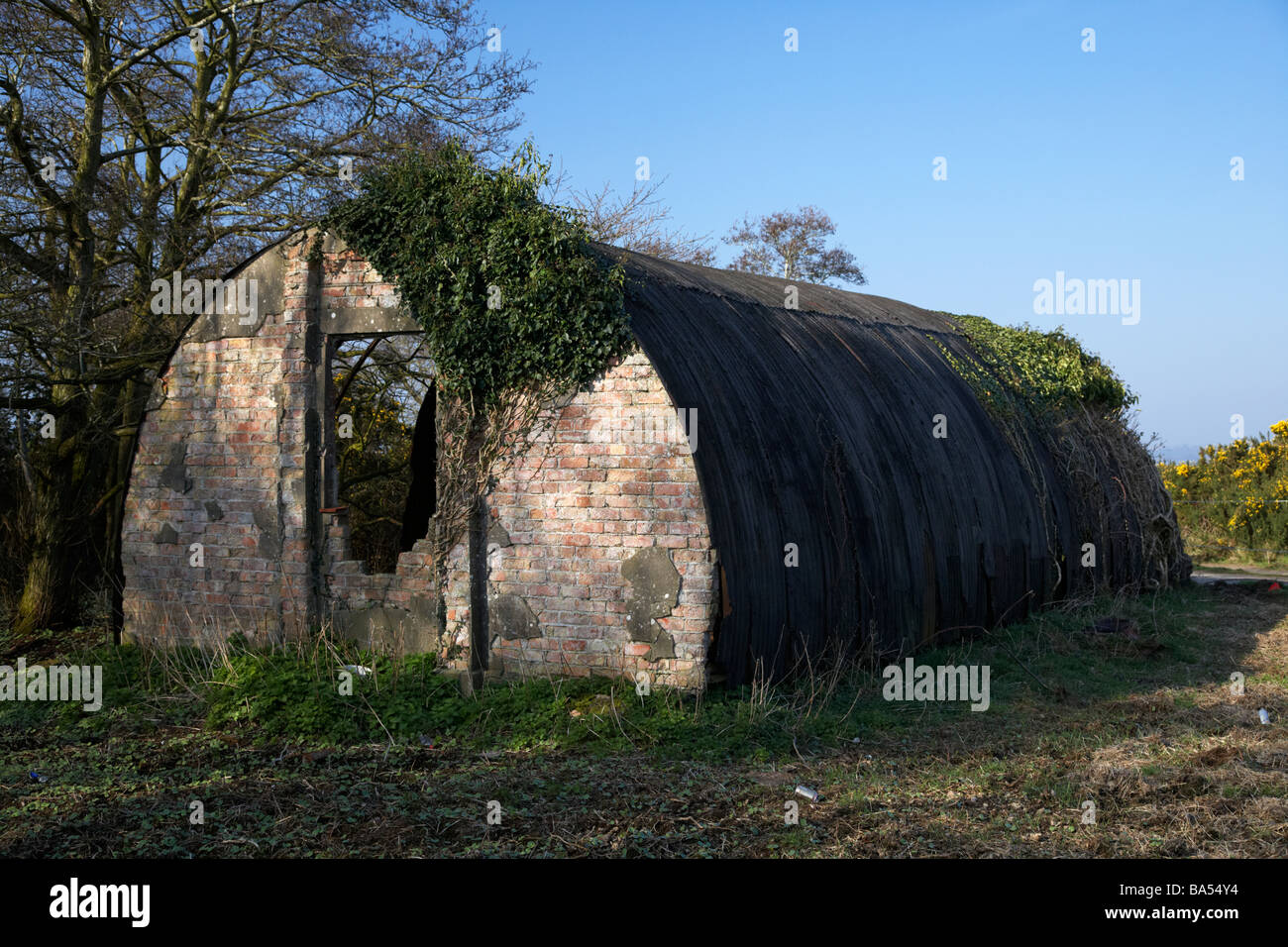 derelict old tin and brick world war two nissen quonset hut on waste land now abandoned from former second world war airbase in county antrim Stock Photo