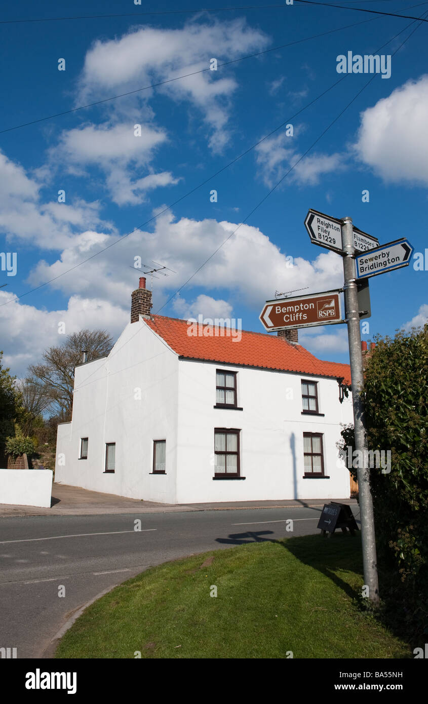 Bright white rendered cottage and a blue sky and signpost Stock Photo