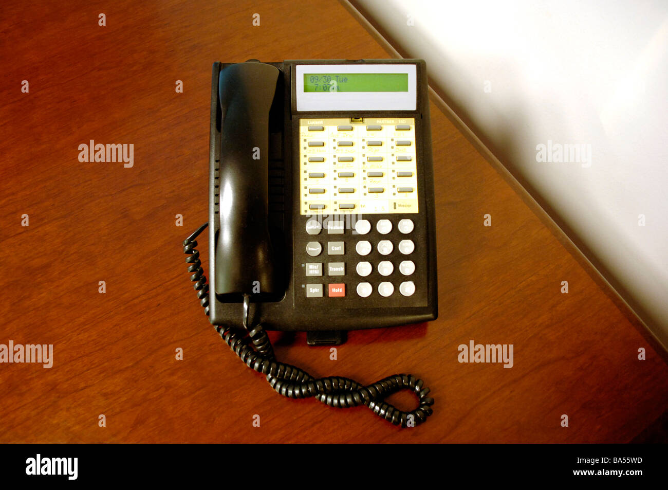 Secretary's office phone with multiple lines, placed on wood grain desk Stock Photo