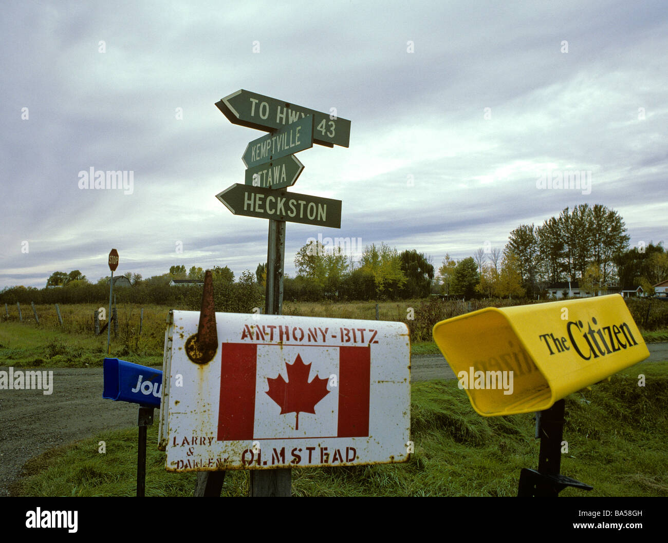 The rural roadsides of Eastern Ontario often have a variety of post boxes Direction signs and newspaper protective tubes Stock Photo