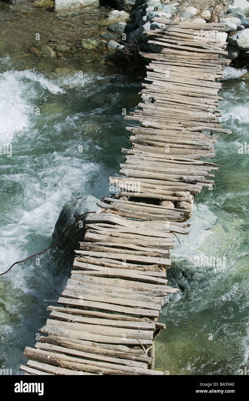 Dodgy wooden bridge over fast flowing river Stock Photo