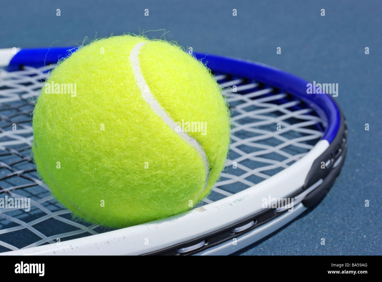 Tennis ball and racket on hard surface Stock Photo