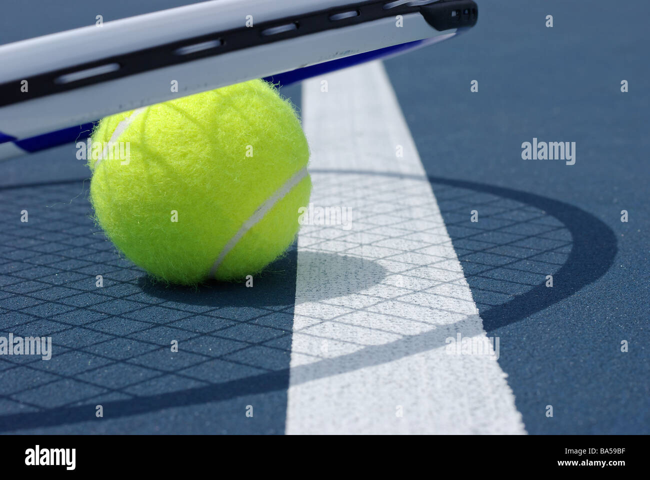 Tennis ball and racket on hard surface Stock Photo