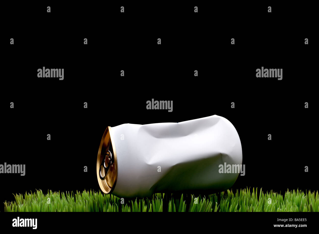A horizontal image of a white crushed soda can tossed on green grass instead of being recycled Stock Photo