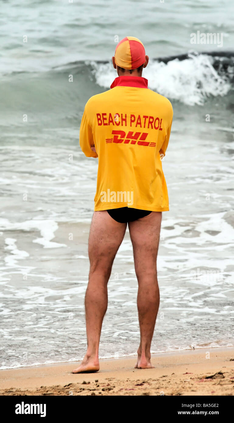 Australian Surf Life Saver at waters edge wearing a DHL Beach Patrol Shirt Port Campbell Victoria Stock Photo