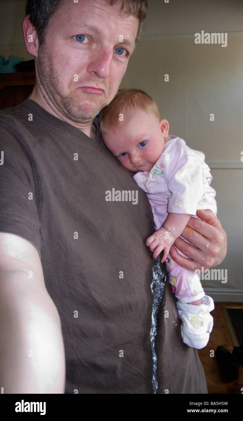 Man holding a baby which has been sick on his t shirt Stock Photo