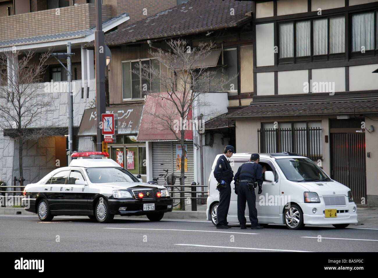 Japanese police officers talking to the driver of a car in Kyoto Japan Stock Photo