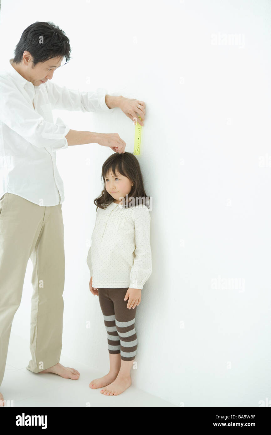 Father measuring daughter height on wall Stock Photo