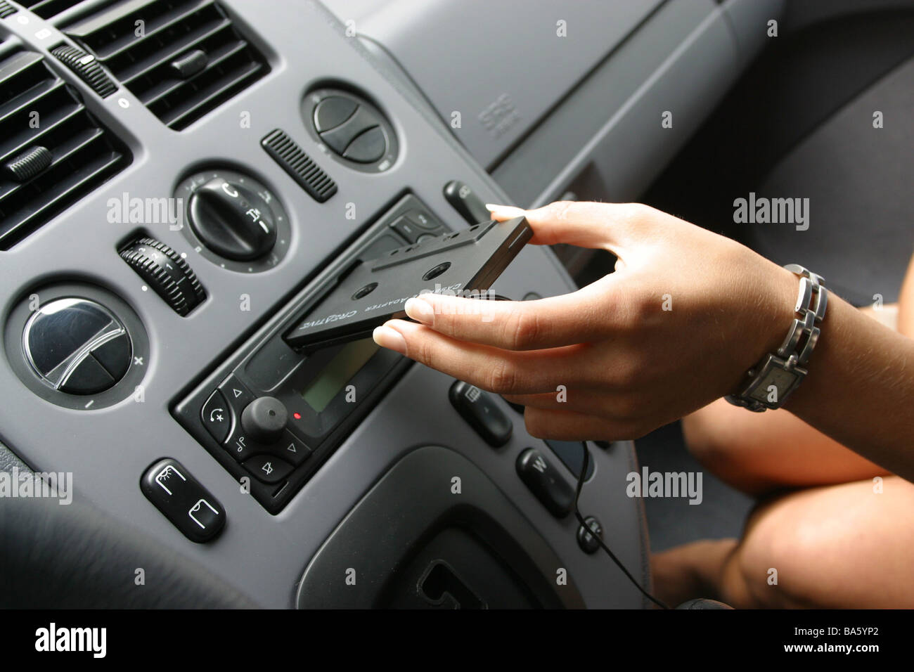 https://c8.alamy.com/comp/BA5YP2/car-indoors-woman-hand-adapter-cassette-car-radio-cassette-shaft-puts-BA5YP2.jpg