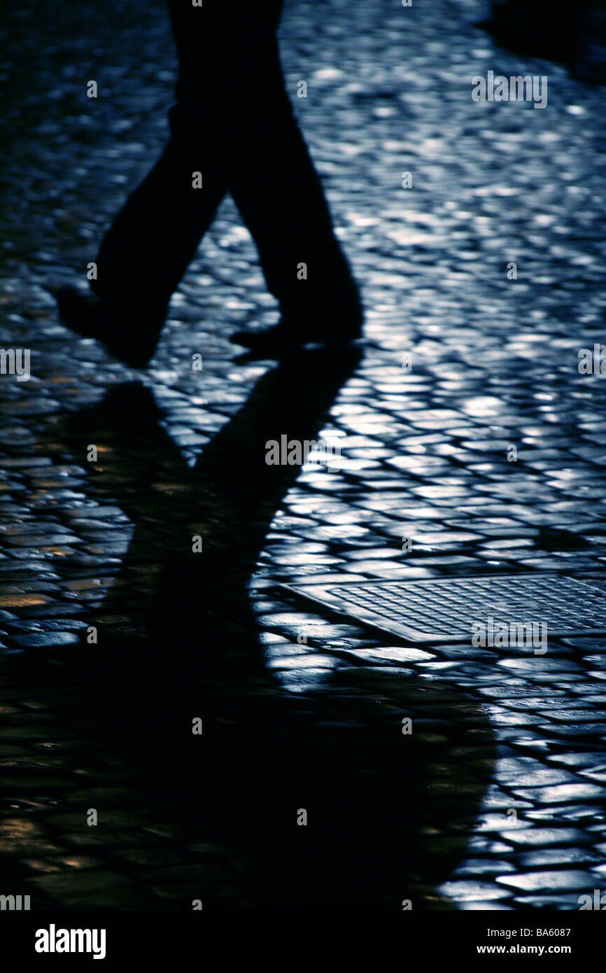 person walking on wet cobbled street at night Stock Photo - Alamy