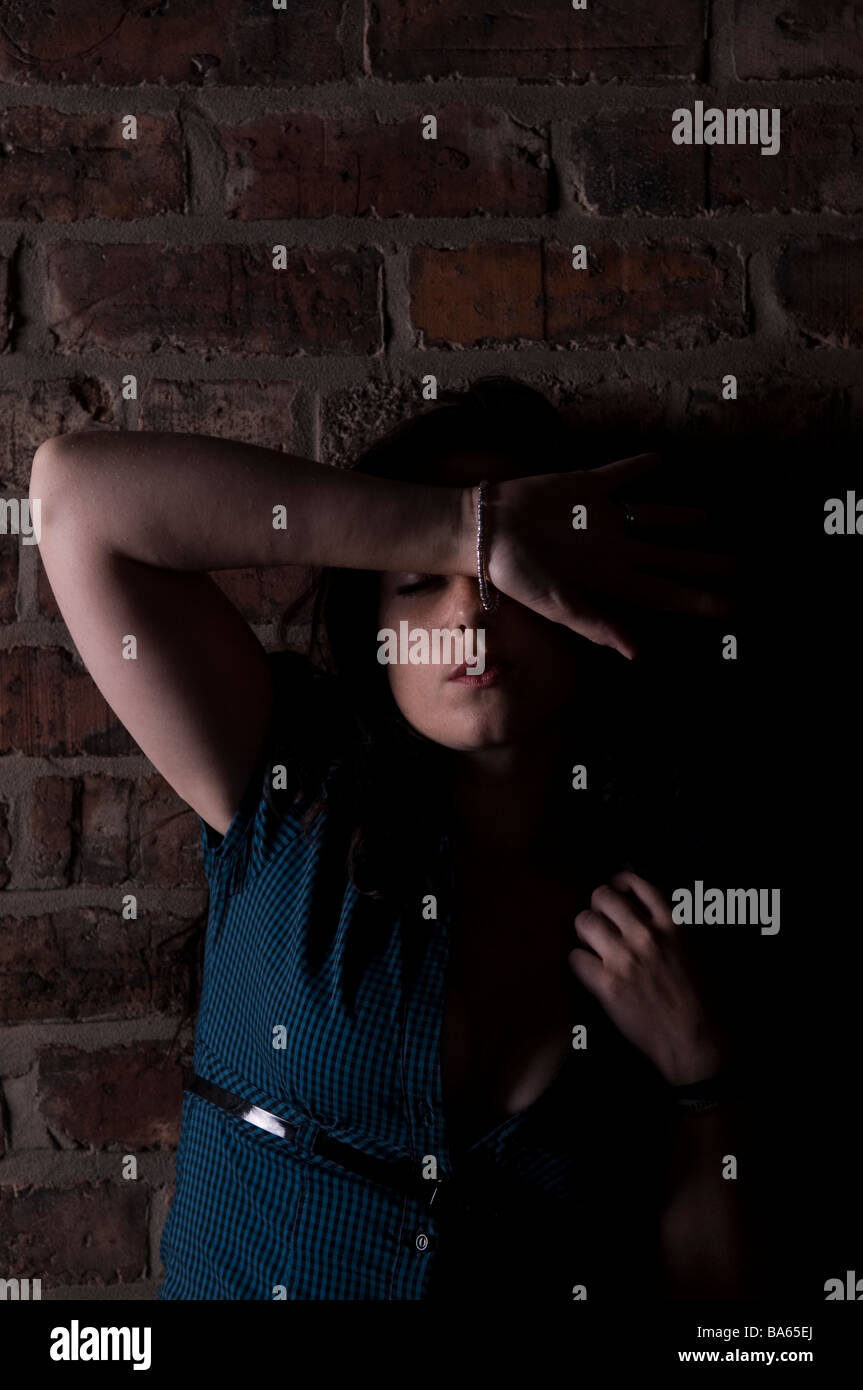 Woman hiding her face in fear in a dark alley Stock Photo
