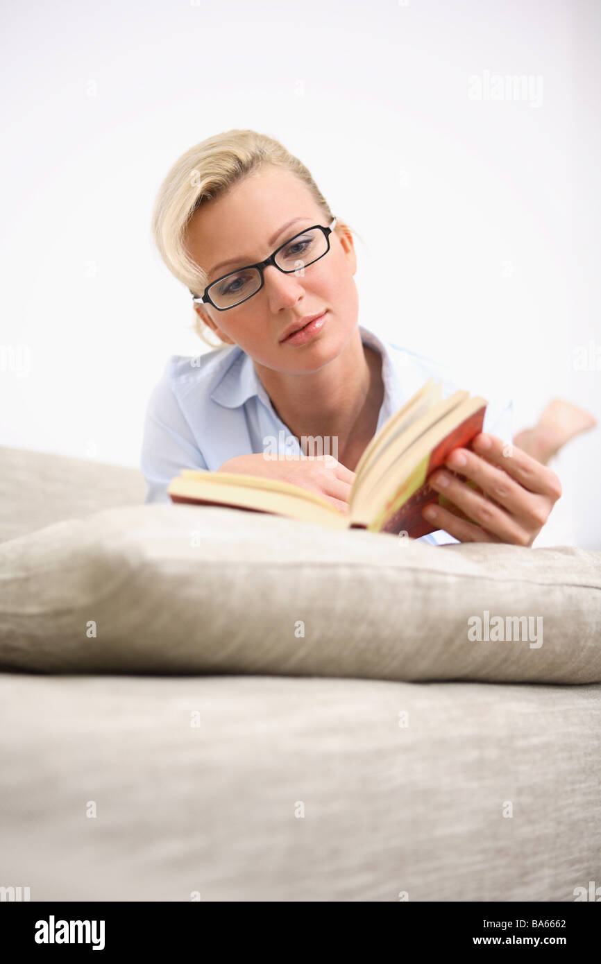 Sofa woman glasses book reads lies relaxation portrait series people women-portrait 30-40 years blond relaxen rest beauty Stock Photo