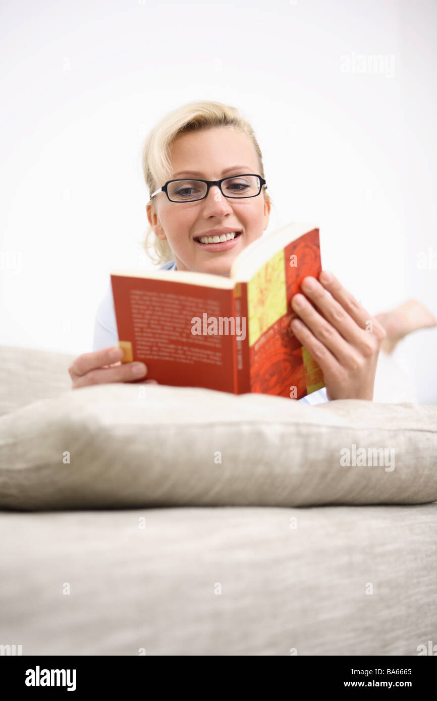 Sofa woman glasses book reads lies relaxation portrait series people women-portrait 30-40 years blond smiles beauty silence Stock Photo