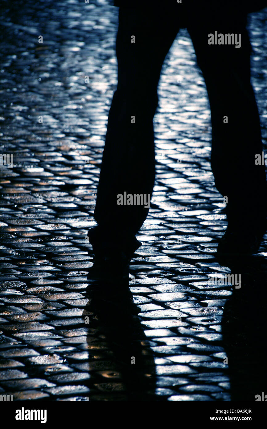 person walking on wet cobbled street at night Stock Photo - Alamy