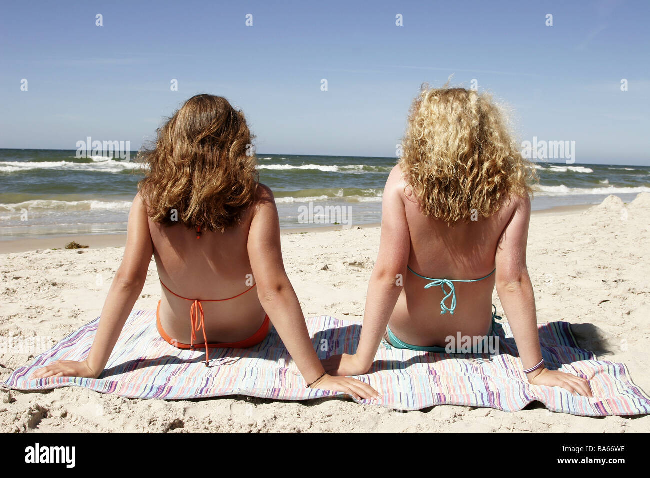 Beach girls two sits back-opinion series people teenagers teenagers friends  13-16 years brunette blond bath-clothing bikini Stock Photo - Alamy