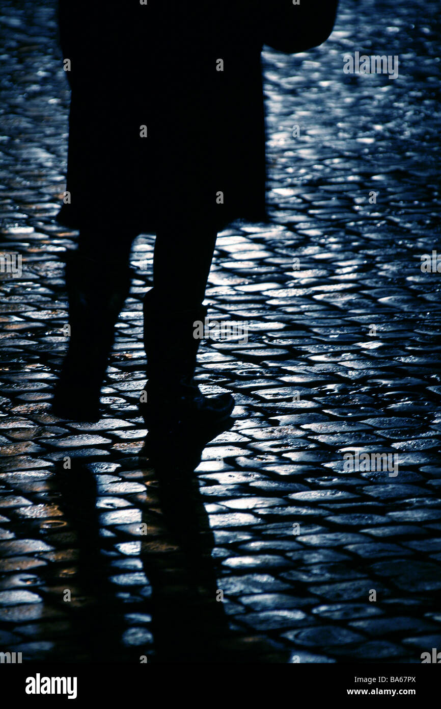 person walking on wet cobbled street at night Stock Photo - Alamy