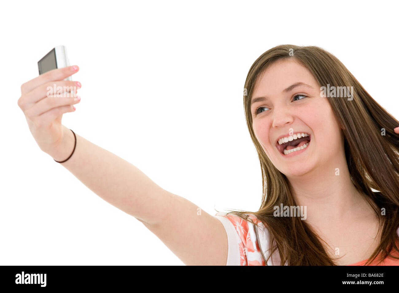 Caucasian teenager using a cell to take a picture of herself on white