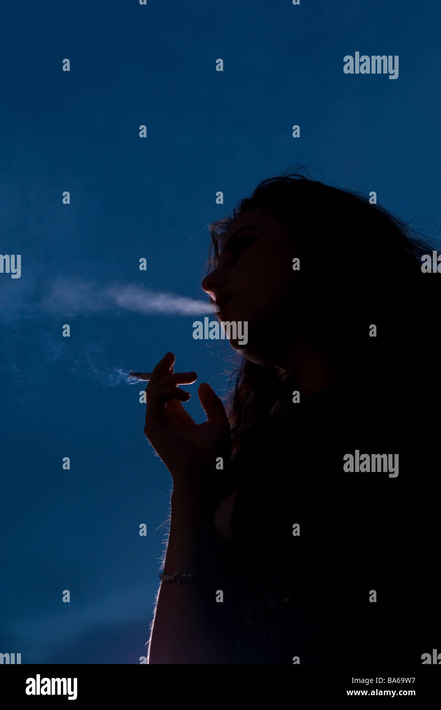 Woman smoking outside at night Stock Photo