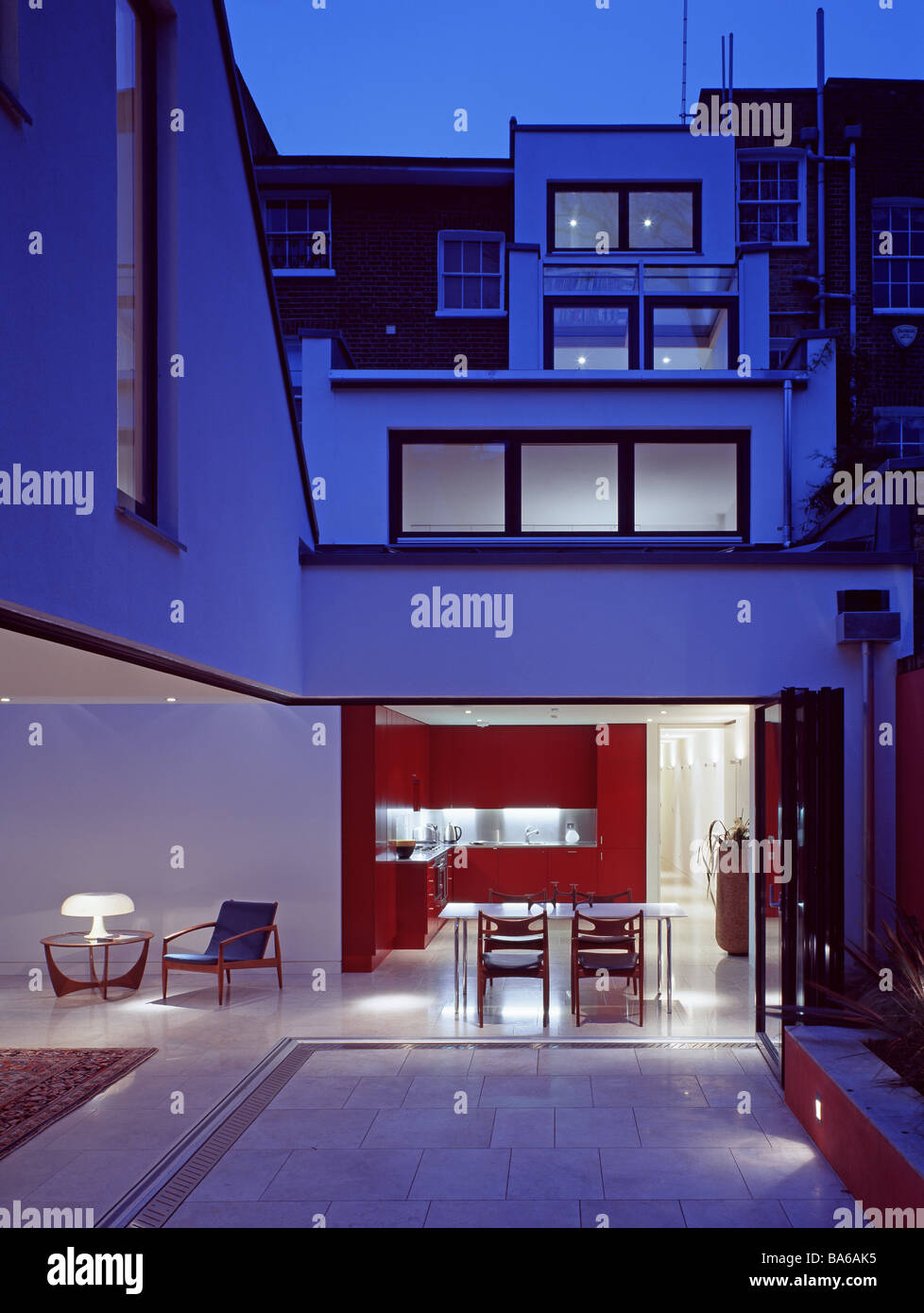 Kitchen and living rooms open to the courtyard at night, GAP house, London, UK. Stock Photo