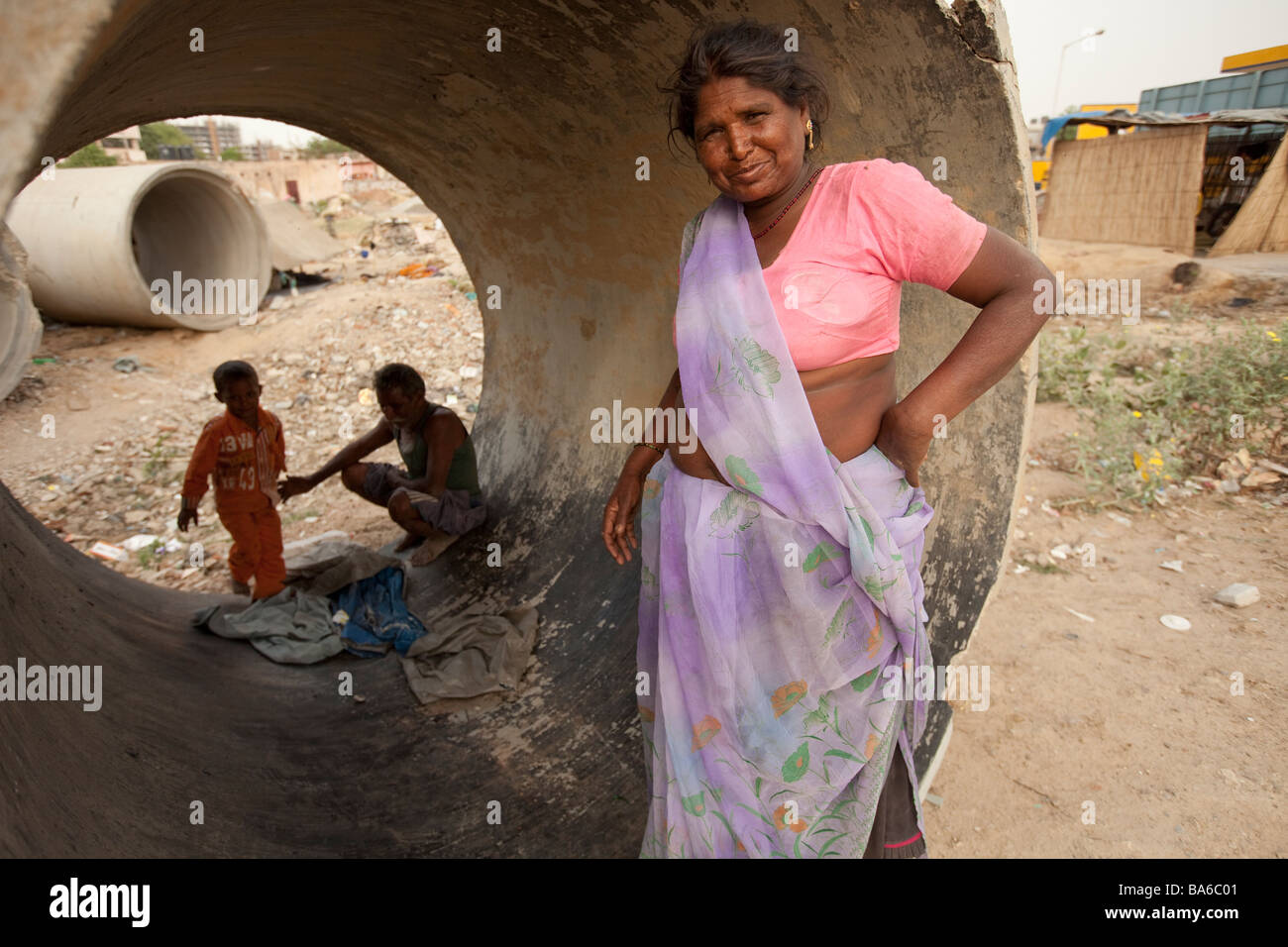 An Indian family squatting among sewerage pipes opposite  construction zone in Gurgaon a satellite city south of Delhi Stock Photo