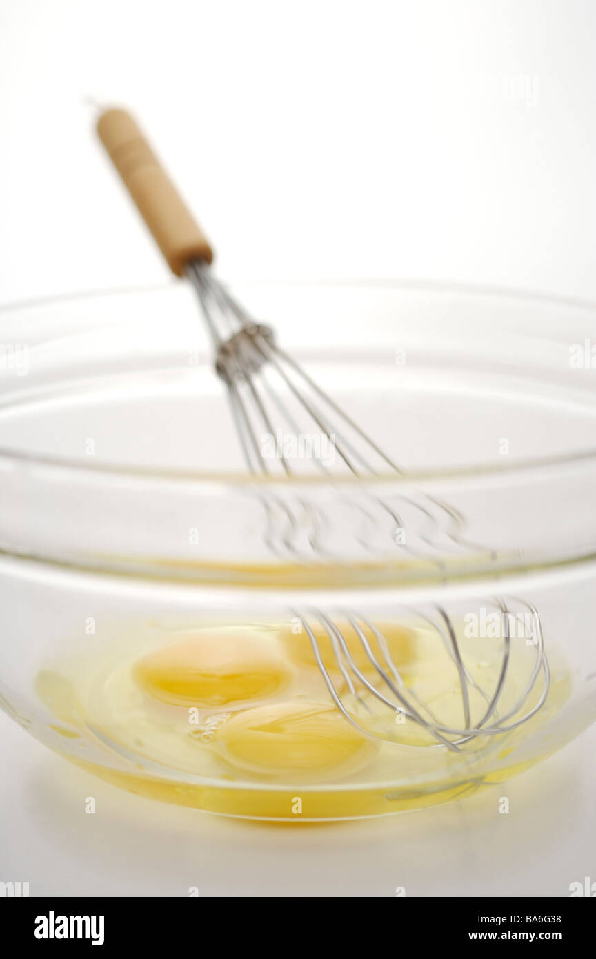 Egg yolks and egg wire whisk in bowl against white background Stock Photo