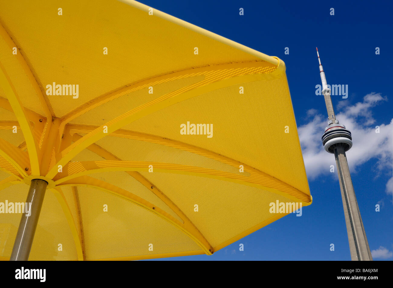 Yellow beach umbrella at urban beach of HTO Park Toronto with CN tower and blue sky Stock Photo
