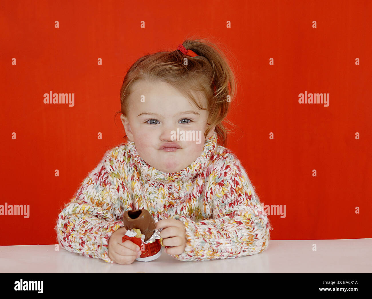 Table child girls eats chocolate-Nikolaus grimace portrait Christmas time people toddler 2-4 years rope-sweaters braid gaze Stock Photo