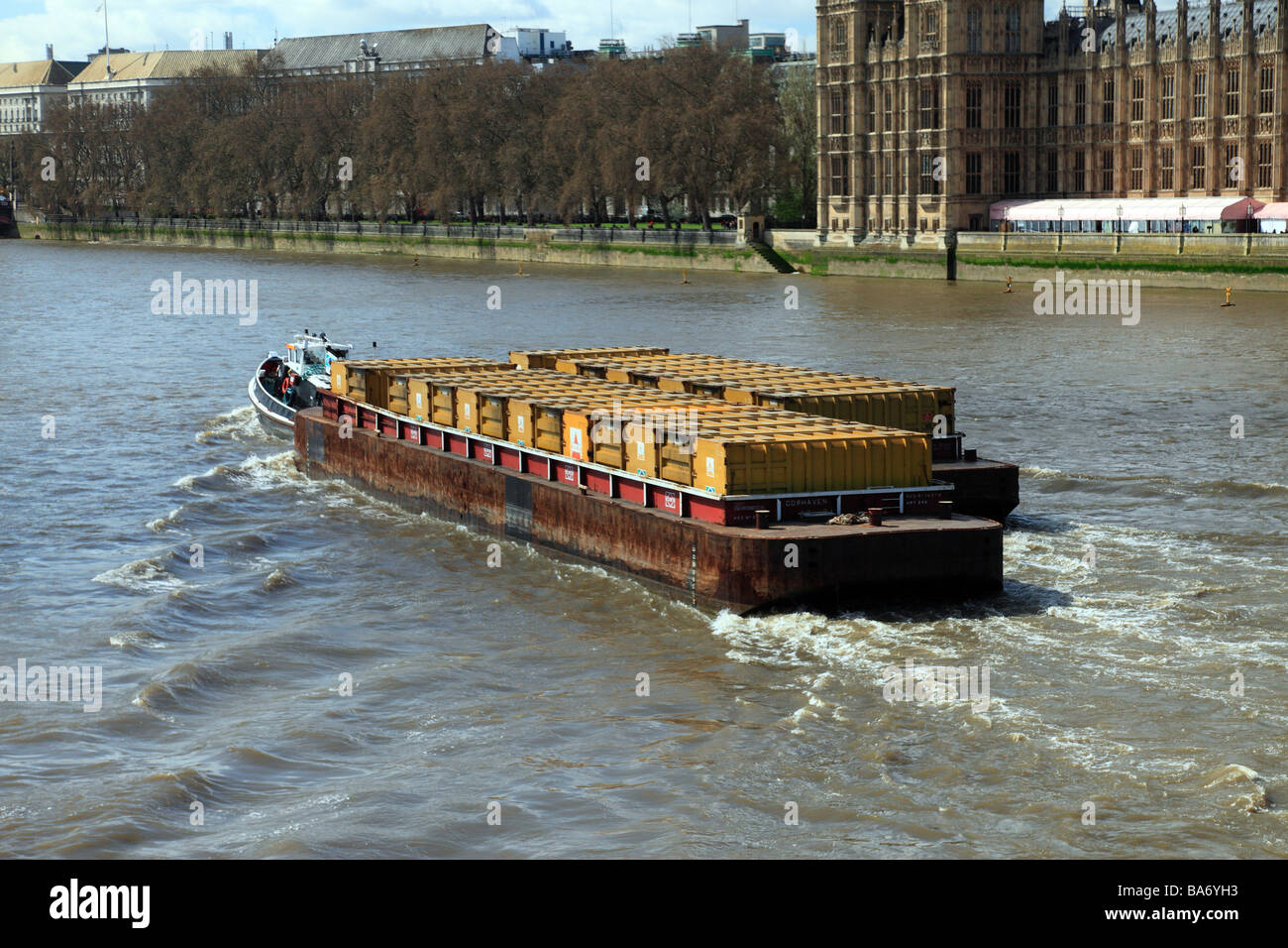 Thames container barge passing the Houses of Parliament London. Stock Photo