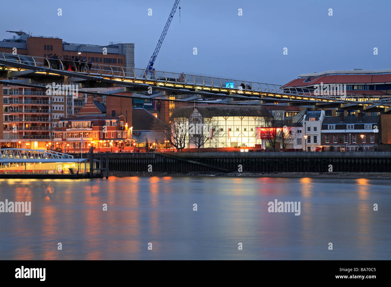 Shakespeare's Globe Theatre below the Millennium Bridge over the River Thames at night, London, England, UK. Stock Photo