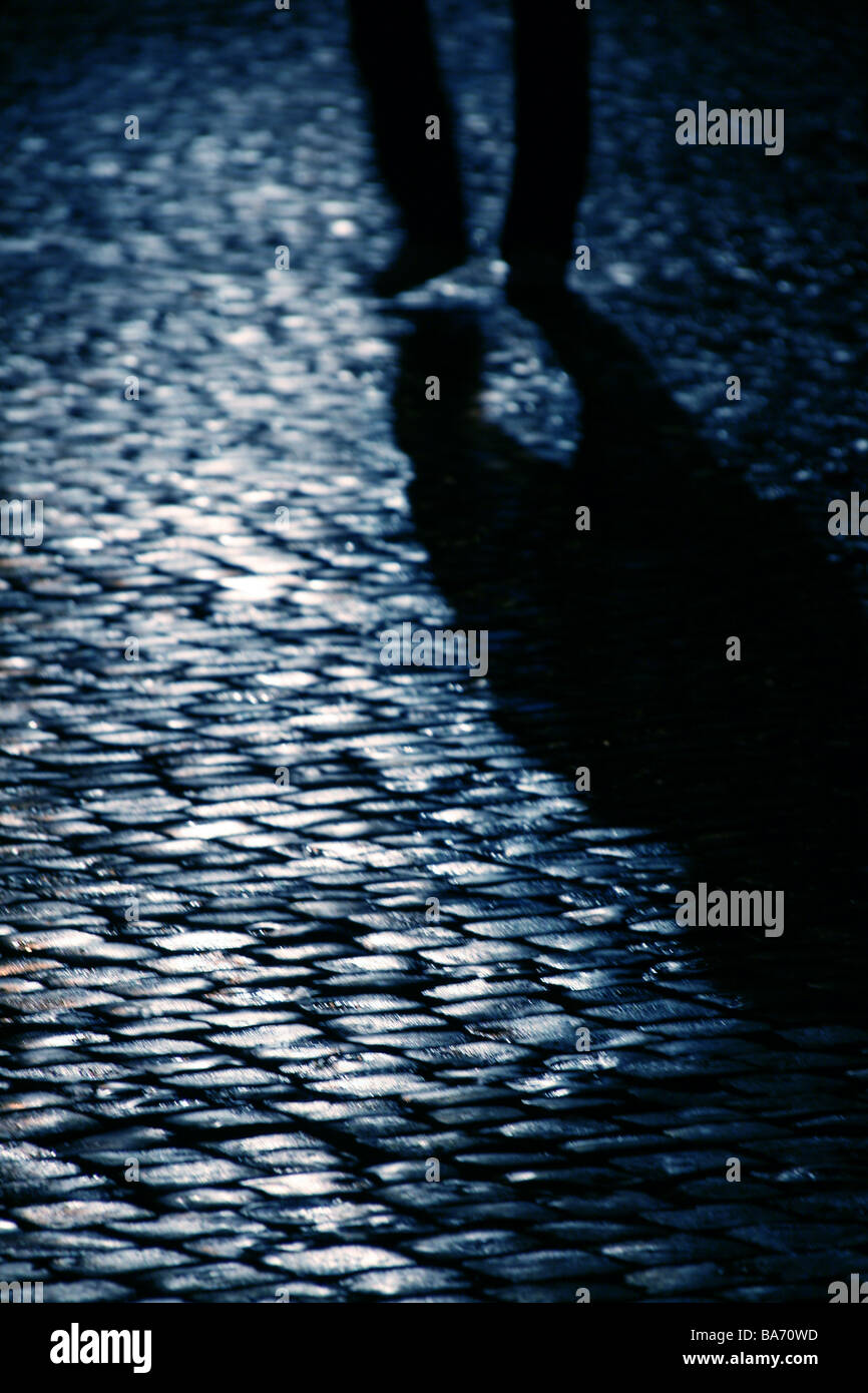 person walking on wet cobbled street at night Stock Photo - Alamy