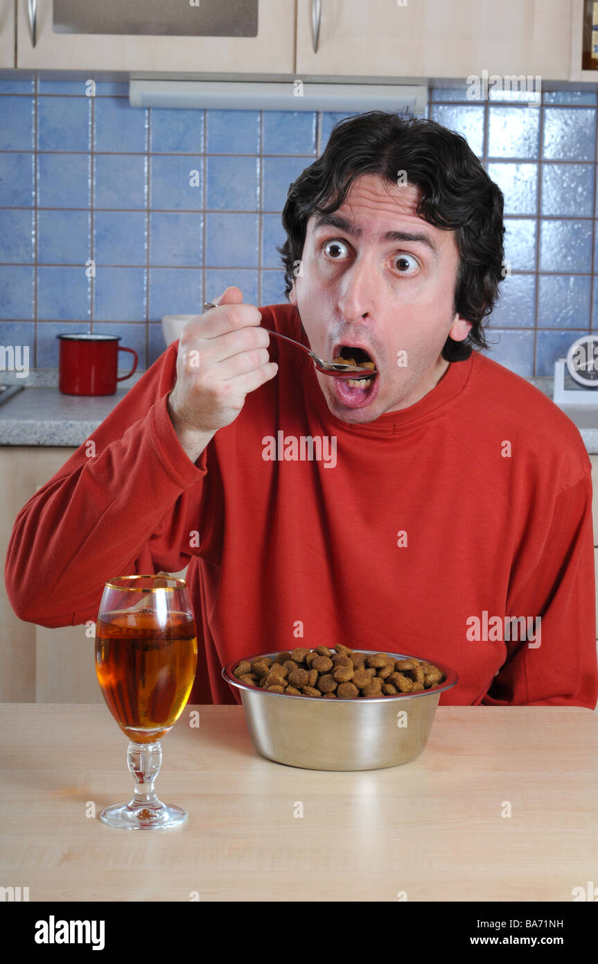 Crazy wild man eating dog s granulated food for dinner. Stock Photo